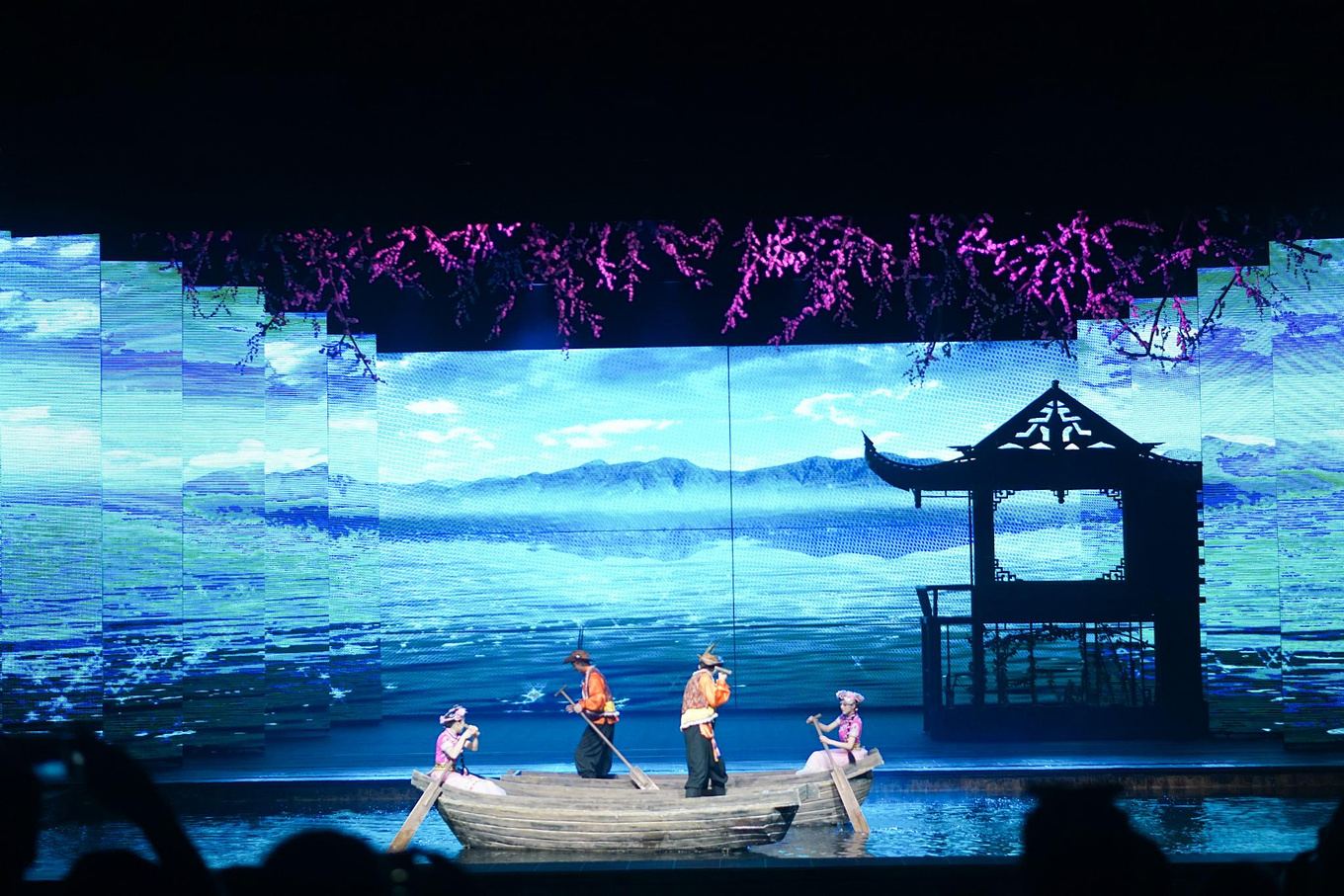 舞台开始泛起了绿水碧波,由暗到明的光幕里,一只小舟缓缓而来,漂亮的