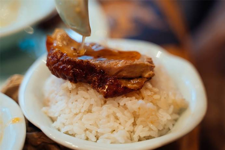 用金屬容器裝好鴨肉端上桌來一碗米飯,把滷油一勺勺澆在飯中,表滿拌勻